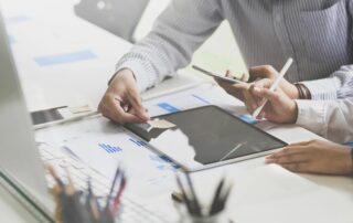 two men discussing numbers on ipad